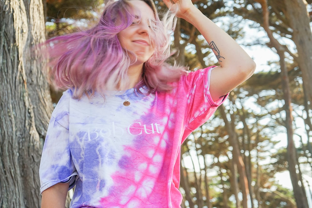 girl in pink t-shirt and blue shorts standing near green trees during daytime