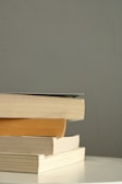 A stack of essay and research books with textured, earthy-toned covers.