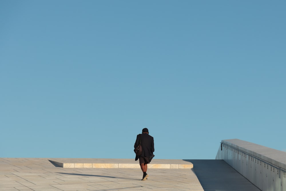 man in black jacket standing on gray concrete floor during daytime