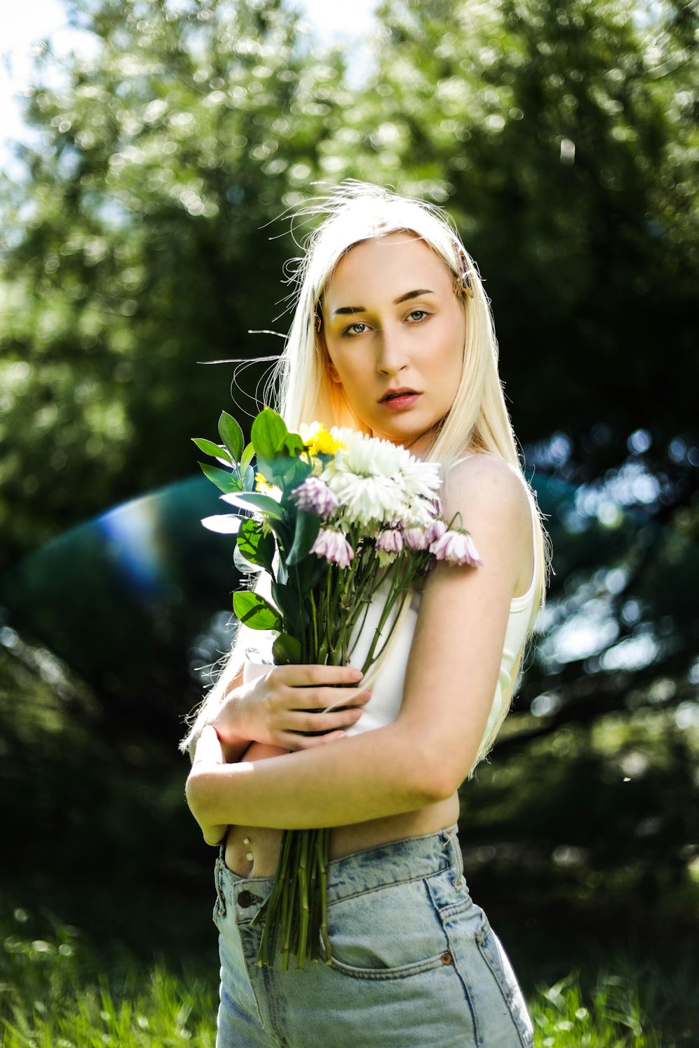 woman in yellow sleeveless dress holding white and purple flowers