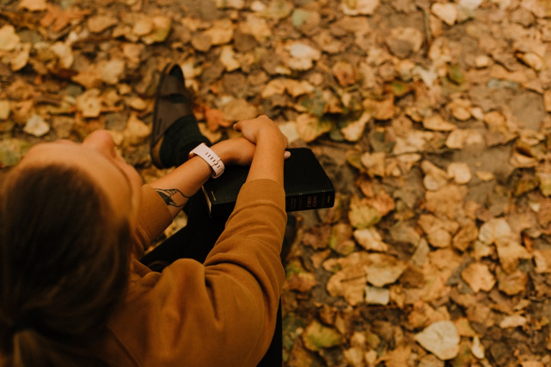 person in brown pants holding black smartphone