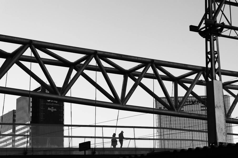 silhouette of 2 person standing on bridge during daytime