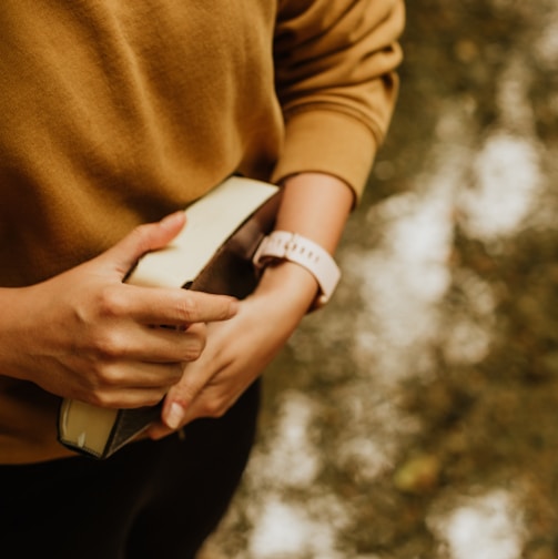 woman in brown long sleeve shirt holding white smartphone