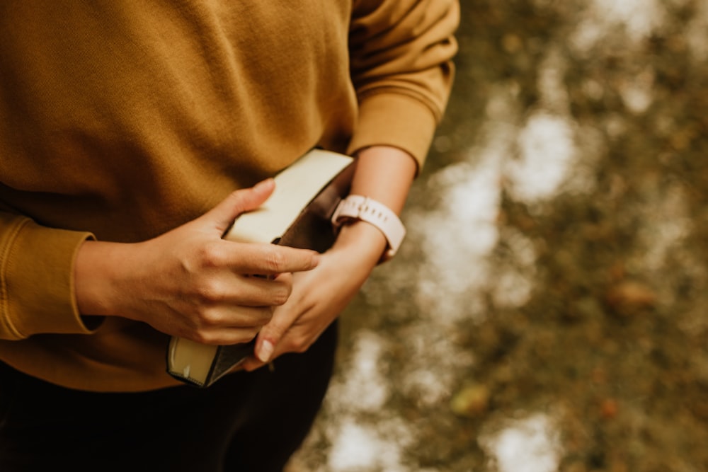 woman in brown long sleeve shirt holding white smartphone