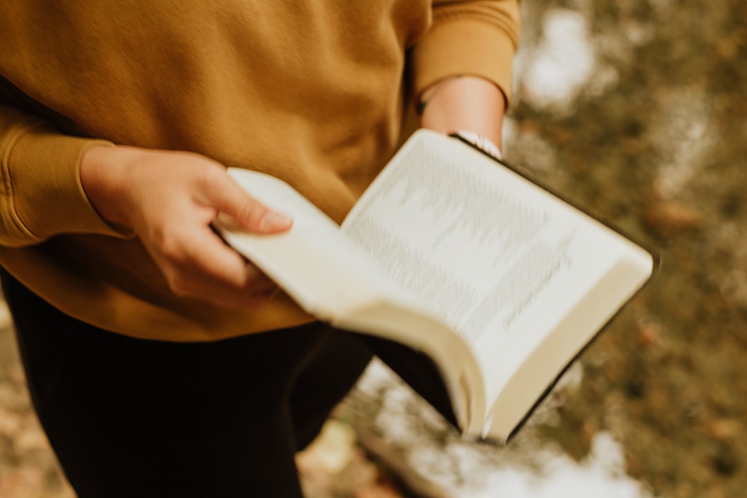 person in brown long sleeve shirt holding white book