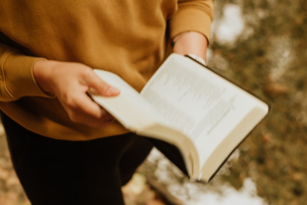 person in brown long sleeve shirt holding white book