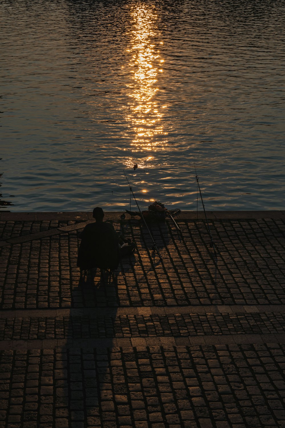 silhouette of man fishing on sea during sunset