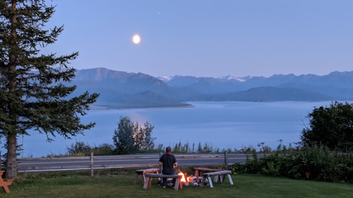 Aloka resting peacefully beside a campfire with monks sharing stories under the stars.