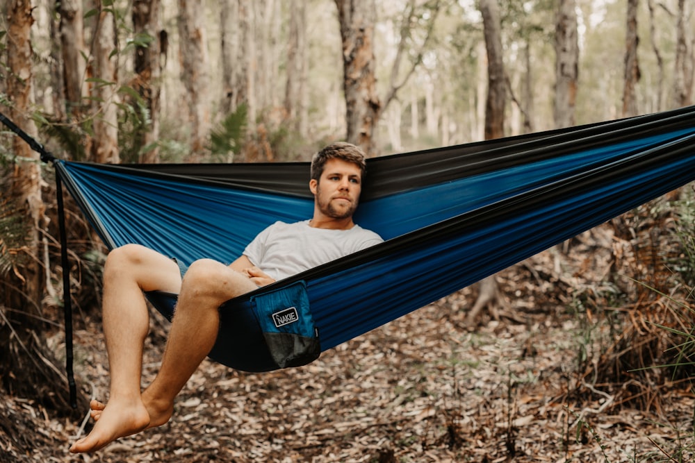 man in white t-shirt lying on blue hammock