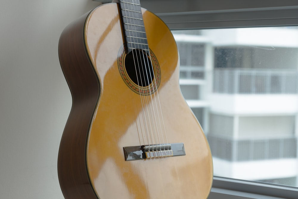 brown acoustic guitar on glass window