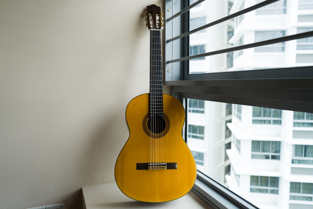 brown acoustic guitar on white wall