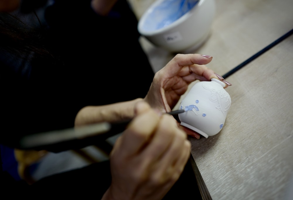 persona sosteniendo una taza de cerámica blanca