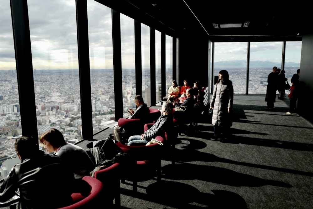 people sitting on red chairs near body of water during daytime