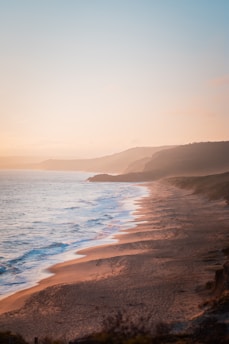 A serene image of the Namibian coastline at sunset, with waves gently lapping the shore near Swakopmund.