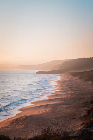Panoramic view of Ericeira coastline at sunset with serene beach and cliffs