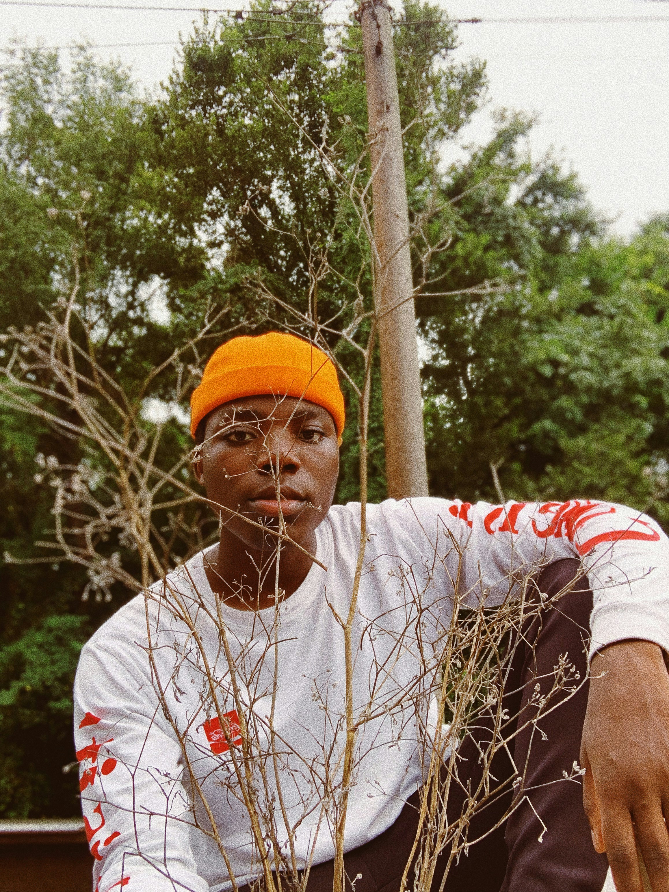 man in white and red crew neck t-shirt and orange cap holding brown stick