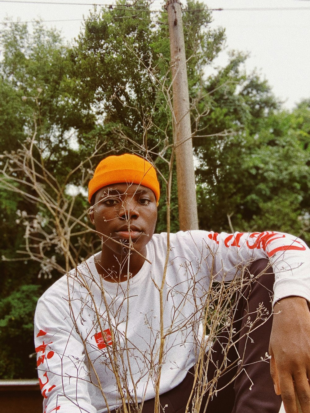 Homme en T-shirt à col rond blanc et rouge et casquette orange tenant un bâton marron