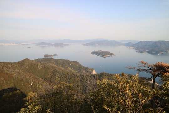 green mountain beside body of water during daytime in Momijidani Park Japan