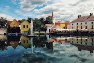 white and brown concrete house beside body of water under blue sky during daytime