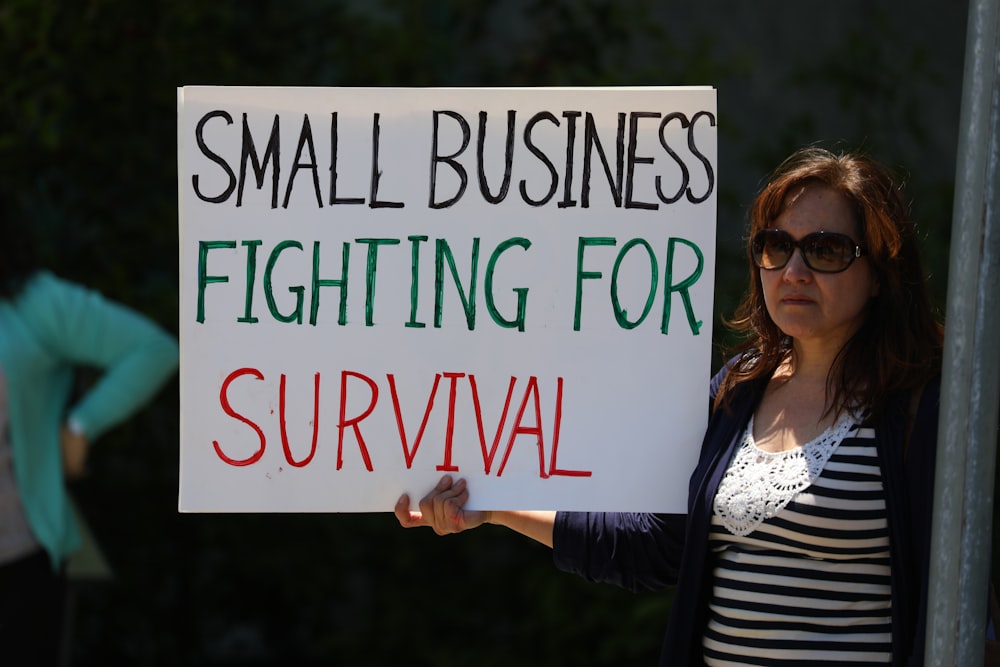 woman in black cardigan holding happy birthday signage