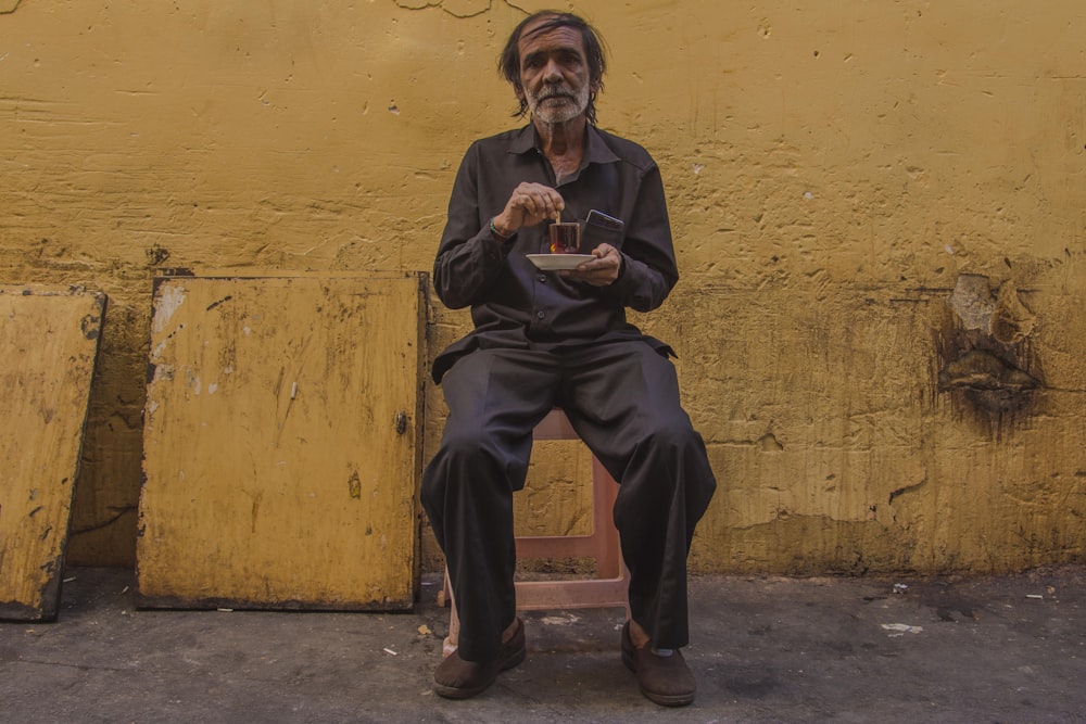 man in black long sleeve shirt and black pants sitting on concrete floor