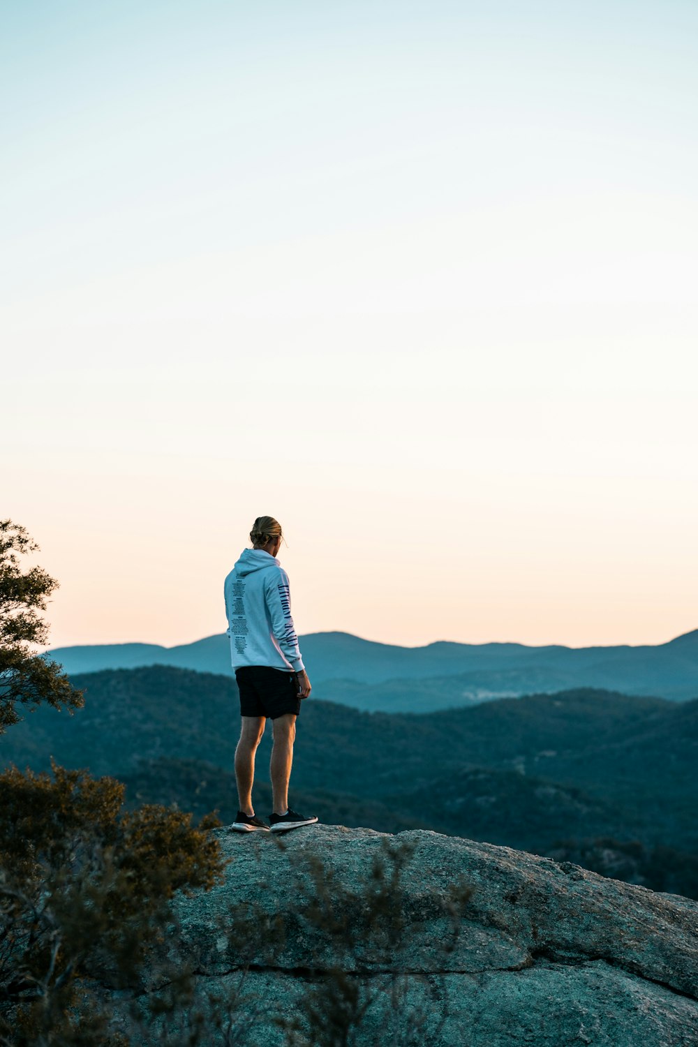 man in blue shirt standing on rock formation during daytime