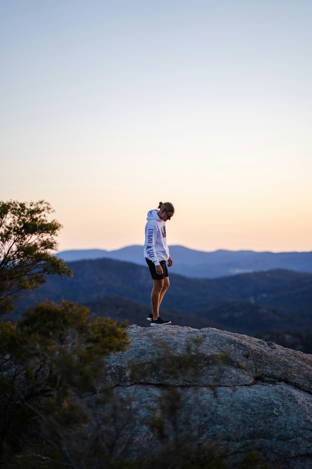 man in white t-shirt and brown shorts standing on rock formation during daytime