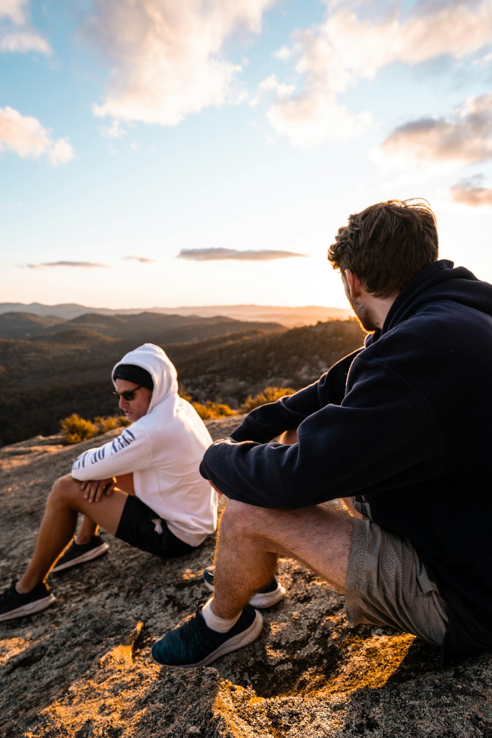 man and woman sitting on rock during daytime