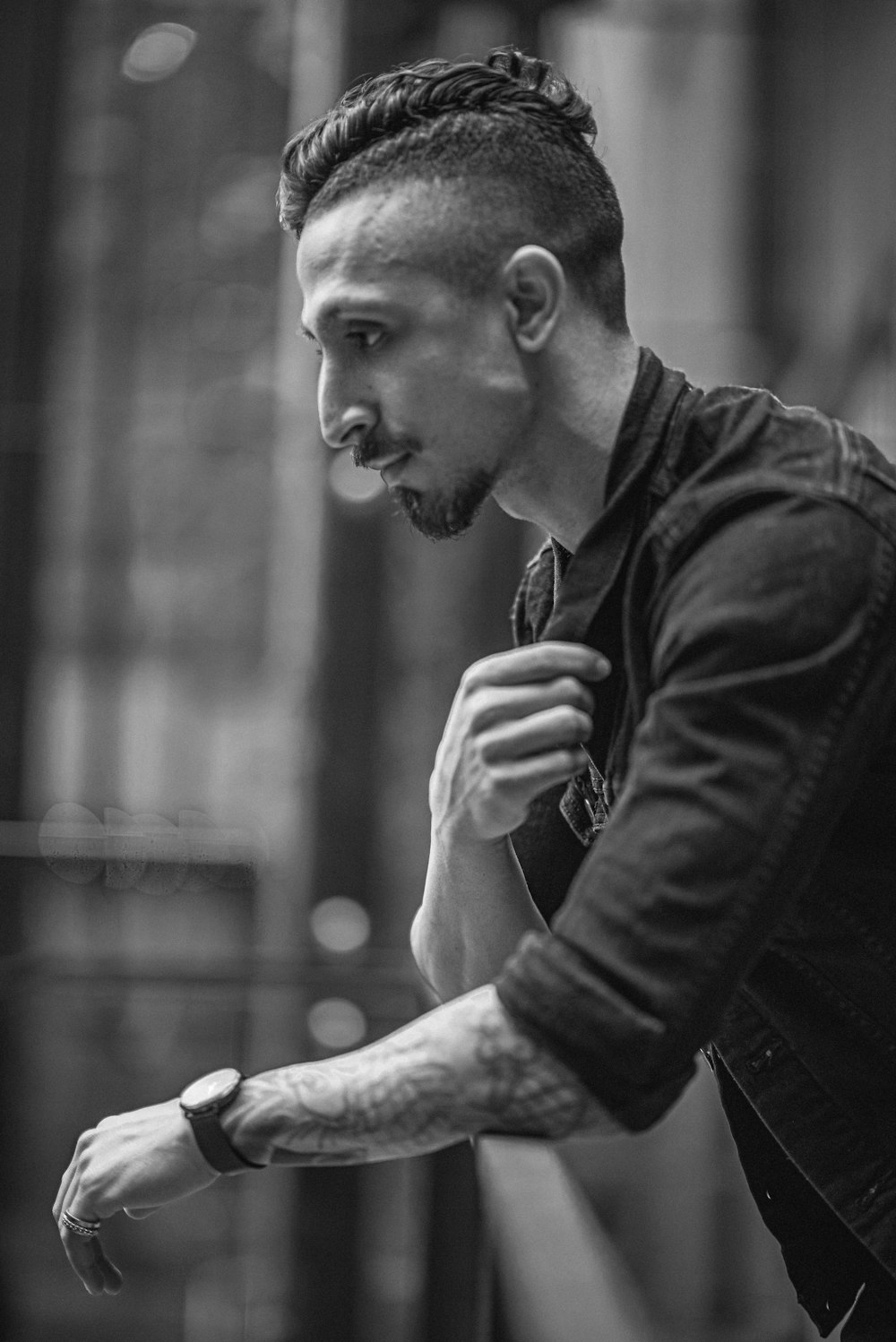 man in black jacket smoking cigarette in grayscale photography