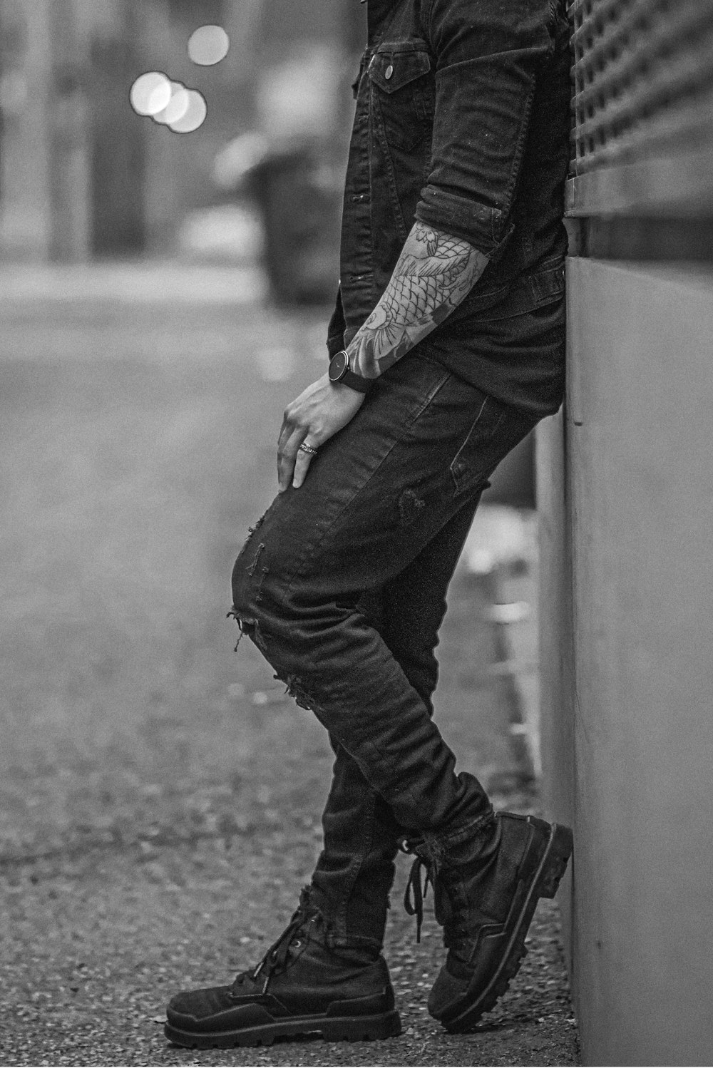 man in black jacket and denim jeans walking on road in grayscale photography