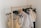 A wooden clothing rack holds an assortment of light, airy garments. The clothes include a variety of dresses and tops in pastel colors, featuring lace and delicate fabrics. Some hangers are wooden while others are black plastic.
