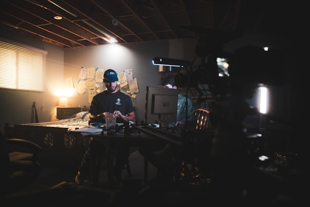 A discreet investigator reviewing surveillance footage on a laptop in a dimly lit room.