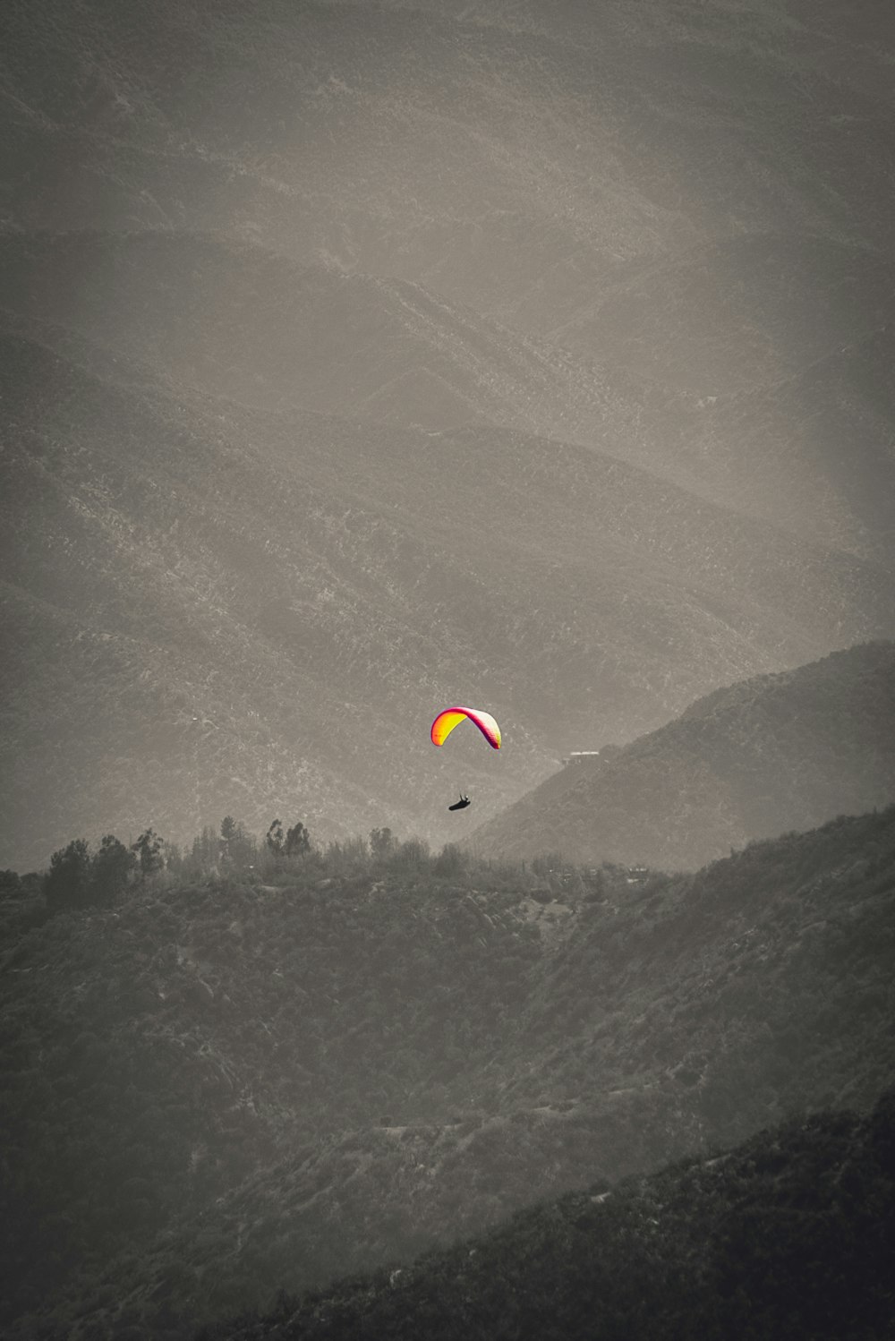 yellow and red parachute over green mountains