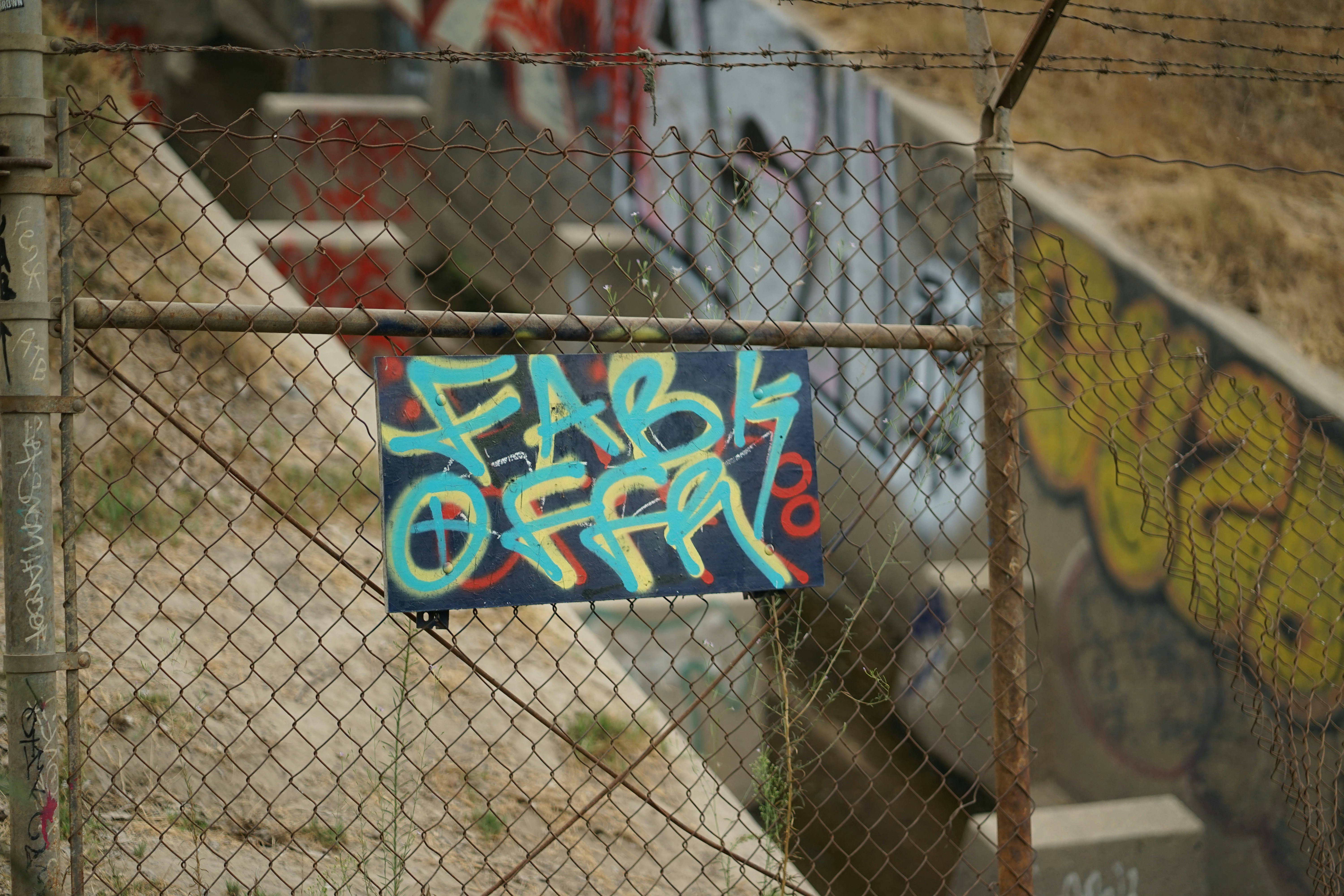 a fence with graffiti on it and a sign on it