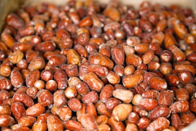 A close-up view of a large pile of red and brown dates, showcasing their glossy texture and slight variations in size and shape.