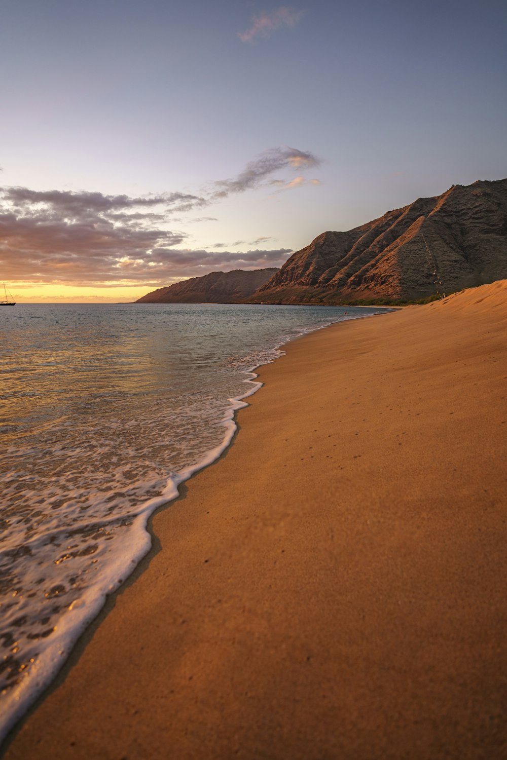 brown sand beach near brown mountain under white clouds during daytime