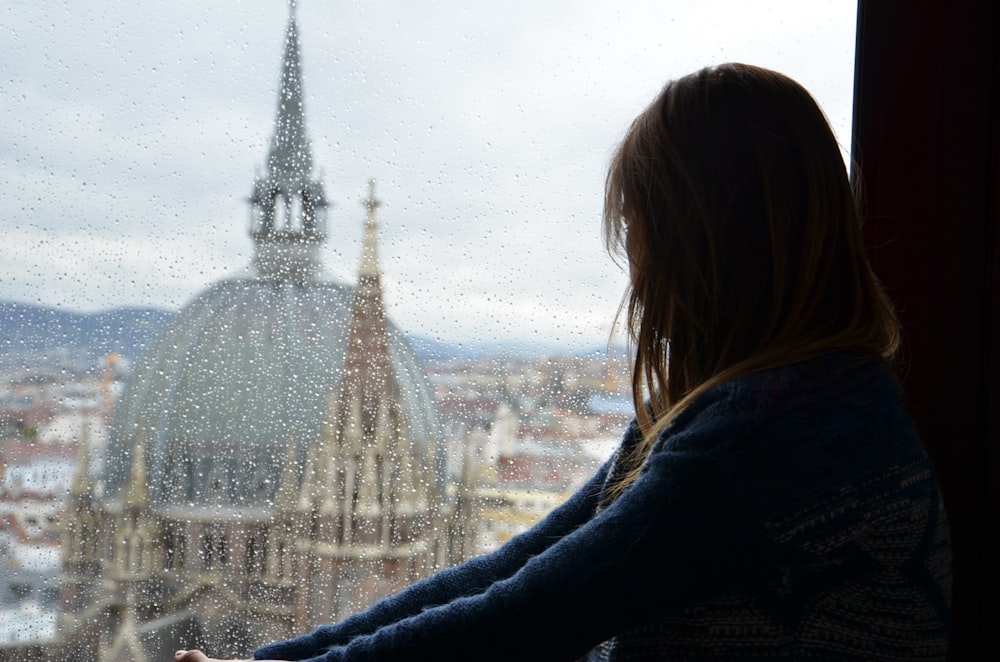 woman in black jacket standing near white tower during daytime