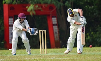 man in white and red jersey shirt and white pants holding brown wooden stick