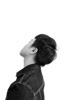 Side profile of a person wearing a simple, original design jacket with subtle stitching details.