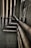 Multiple interconnected pipes run vertically and horizontally along the corner of a slightly worn and grimy wall. The pipes have a weathered and rusty appearance, suggesting they have been in place for some time. Some cables are also visible next to the pipes.