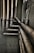 Multiple interconnected pipes run vertically and horizontally along the corner of a slightly worn and grimy wall. The pipes have a weathered and rusty appearance, suggesting they have been in place for some time. Some cables are also visible next to the pipes.