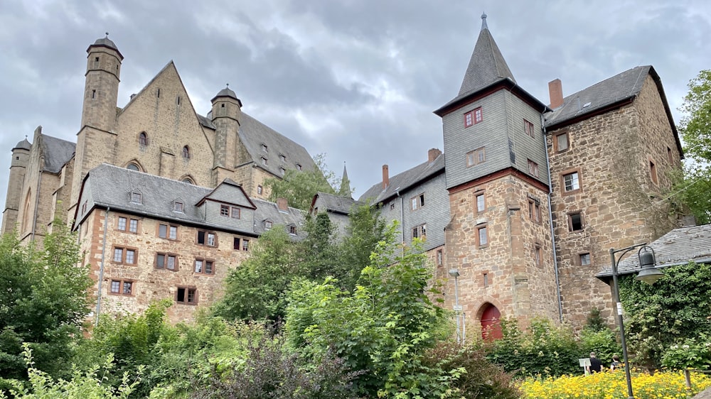 Braunes Betongebäude in der Nähe grüner Bäume unter weißen Wolken tagsüber