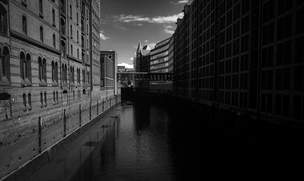 grayscale photo of river between buildings