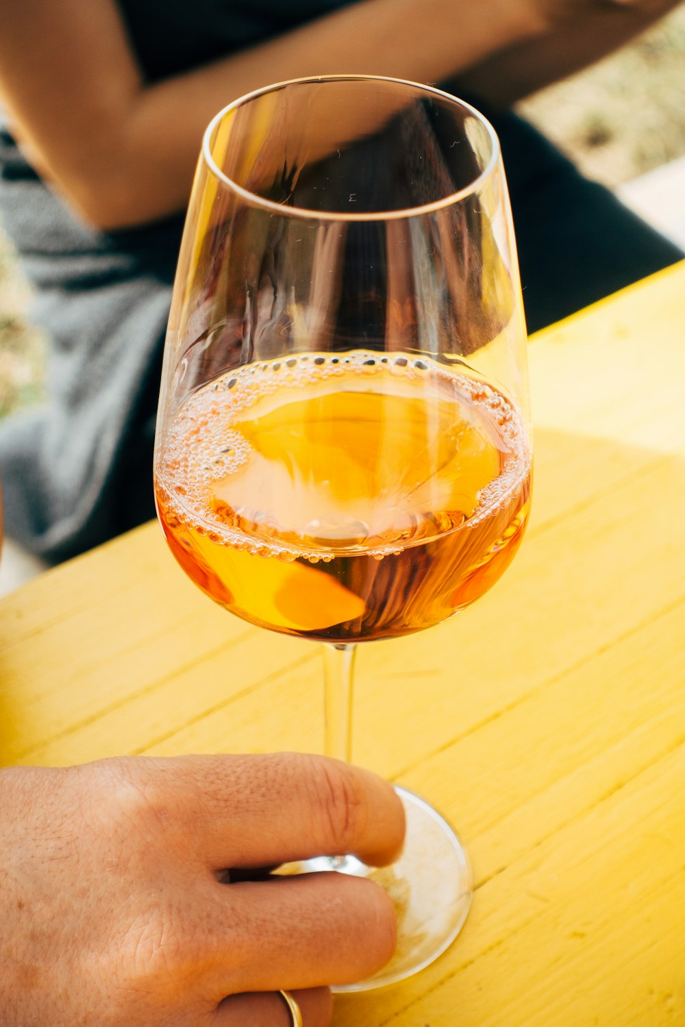 person holding clear drinking glass with orange liquid