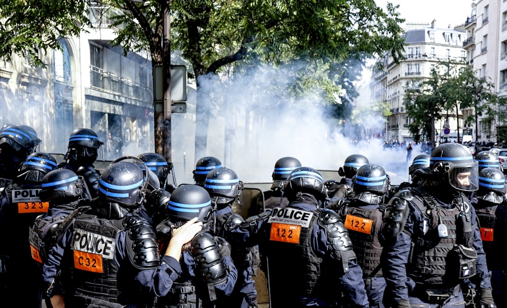 Groupe d’hommes portant un casque noir et bleu debout près d’arbres verts pendant la journée