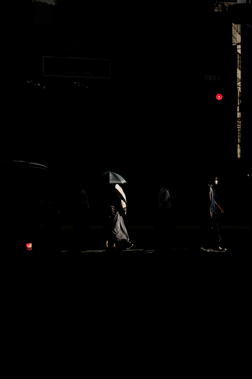 silhouette of person holding umbrella walking on street during night time
