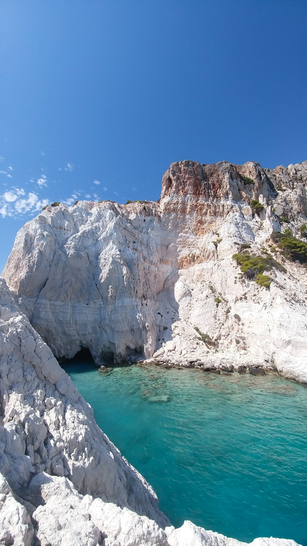 white rocky mountain beside blue sea under blue sky during daytime