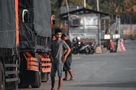 A convoy of black and silver trucks lined up against a minimalist industrial backdrop.