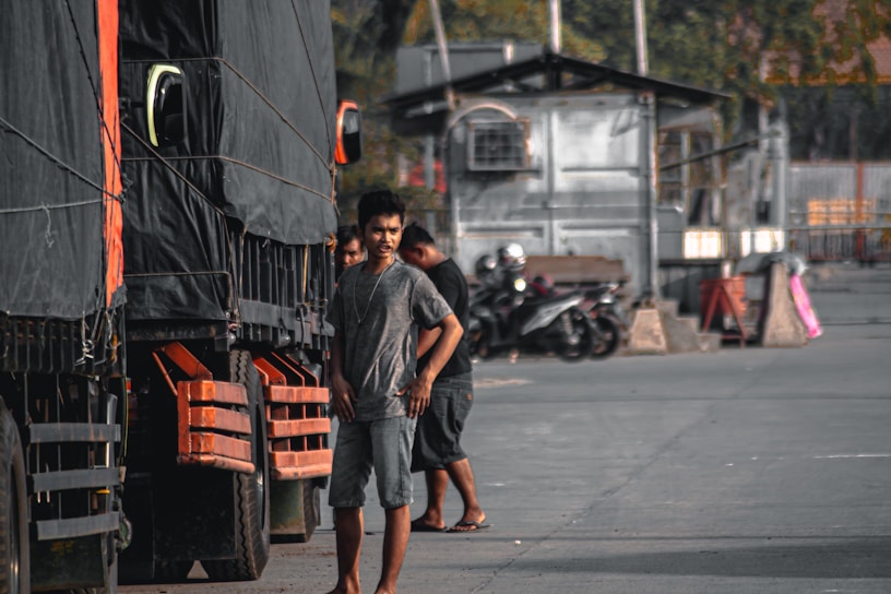 A busy truck stop with several trucks lined up, drivers chatting and preparing for their next load.
