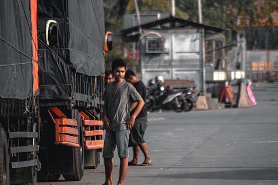 A confident dispatcher speaking on a headset with trucks lined up in the background.